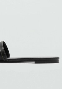 Sandală neagră, cu talpă plată, din material sintetic neted, detalii cusute pe curelele superioare și un design minimalist.