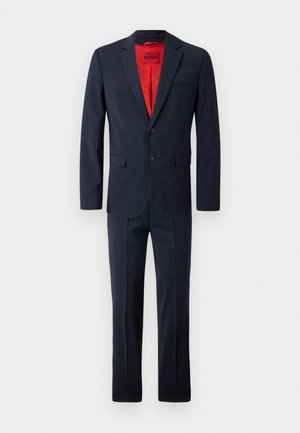 Navy suit set featuring a tailored blazer with two buttons, notch lapels, and matching trousers. Red inner lining adds contrast.