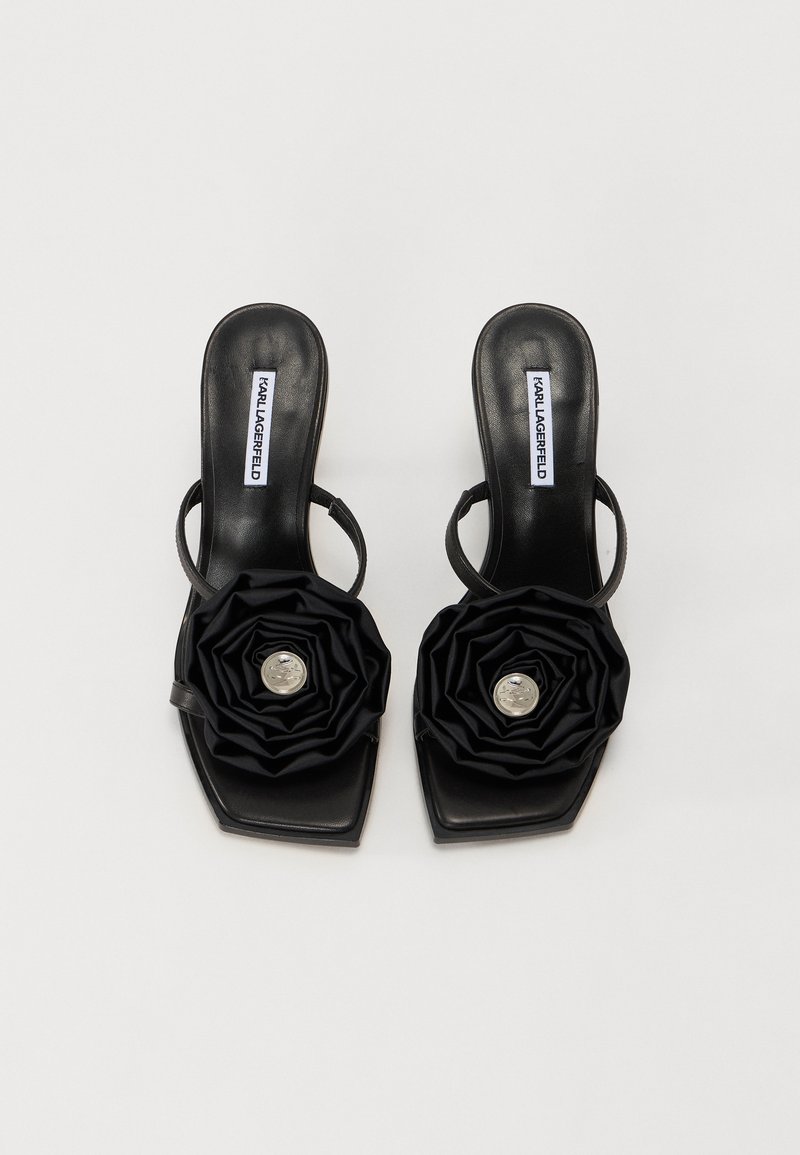 Schwarze High-Heels Sandalen mit quadratischer Zehenpartie und dünnen Riemen. Verziert mit einem großen, gerafften Blumenmotiv und einer silbernen Mitte.