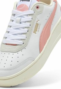 PUMA CA Match tornacipő fehér bőrből pink és bézs akcentusokkal. Perforált orral, fehér fűzőkkel és texturált gumitalppal rendelkezik.