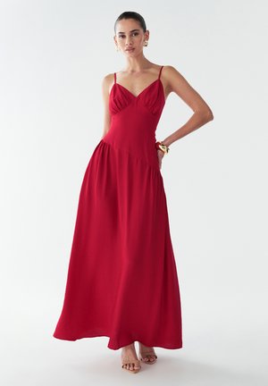 Red maxi dress with spaghetti straps, fitted bodice, and flared skirt. Lightweight fabric, smooth texture, and subtle gathering details.