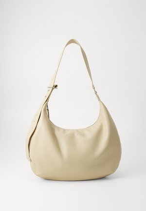 Sac à épaule en cuir beige avec une forme courbée, une bandoulière réglable et un détail de logo embossé, présentant une texture lisse et un design minimaliste.