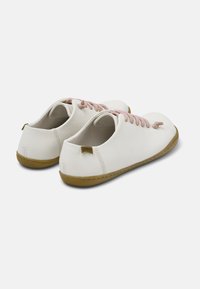 Scarpe di pelle bianche con lacci rosa, punta rotonda e suola in gomma flessibile. Presentano un piccolo tag con il logo sul tallone.