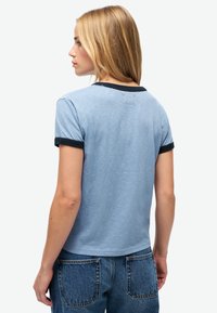 Lichtblauw T-shirt met korte mouwen, voorzien van een ronde zwarte kraag en mouwen. Gemaakt van zacht katoen, met een relaxte pasvorm en een licht cropped ontwerp.