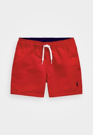 Bañador rojo hecho de un tejido ligero. Cuenta con una cintura elástica con un cordón blanco y un pequeño emblema en azul oscuro.