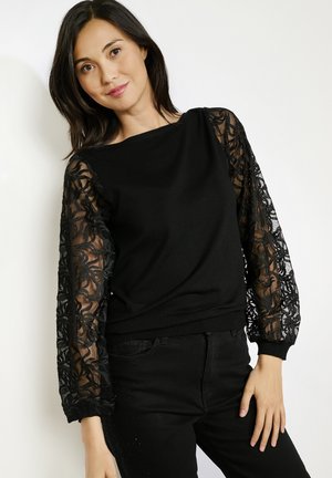 Schwarzer Pullover mit transparenten Spitzenärmeln, die mit floralen Mustern verziert sind. Glatte Textur des Körpers, runder Halsausschnitt, gerippter Saum und taillierte Bündchen.