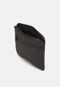 Borsa a zip in nylon nero con superficie texture, dotata di una tasca frontale e di un'etichetta con il marchio nella parte anteriore bassa. Design minimalista con apertura superiore.
