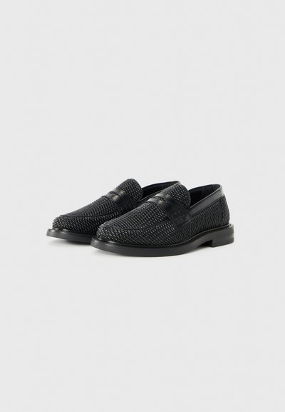 Schwarze Loafer mit einem gewobenen Mesh-Obermaterial und glatten Lederakzenten. Flache Sohle und niedriger Absatz. Die strukturierte Oberfläche verleiht einen modernen Akzent.