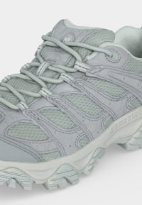 Chaussure de randonnée Merrell grise et vert clair avec semelle épaisse à crampons et lacets solides bouclés, vue de près de côté et de dessus.