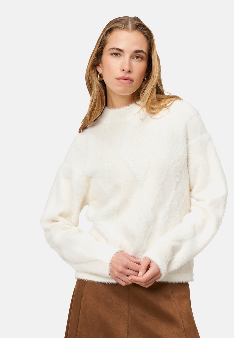 Pull blanc texturé avec un motif en losange, col rond et manches longues, associé à une jupe en daim marron. Apparence douce et confortable.
