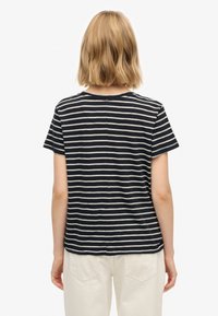 Koszulka w paski w kolorach granatowym i kremowym, z krótkimi rękawami, okrągłym dekoltem i prostym krojem. Wykonana z lekkiego, miękkiego materiału.