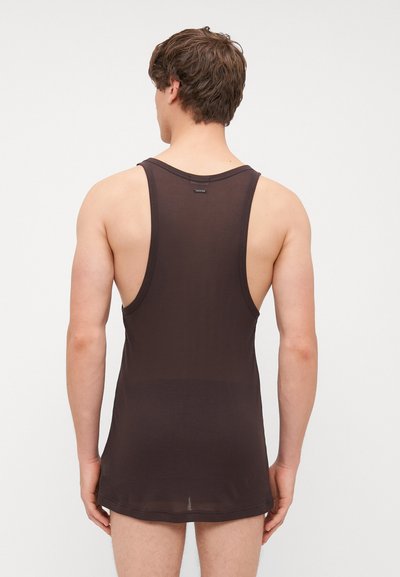 Débardeur marron foncé à côtes avec un design dos nageur, fabriqué en matériau léger et respirant, avec une étiquette au niveau du cou.