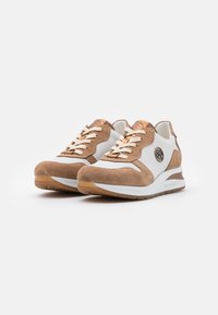 Sneakers con lacci in suede color crema e pelle bianca, caratterizzati da un design perforato, lacci di colore chiaro e un accento con logo sul lato.