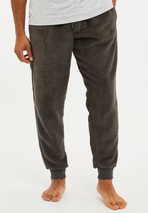 Pantalons de jogging moelleux, gris foncé, fabriqués dans un matériau doux et texturé, avec des poignets élastiques et une taille à cordon. Pas de poches visibles.