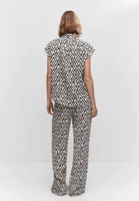 Ensemble de chemise et de pantalon large à motif zigzag noir et blanc. Manches courtes et coupe ample avec une texture lisse.