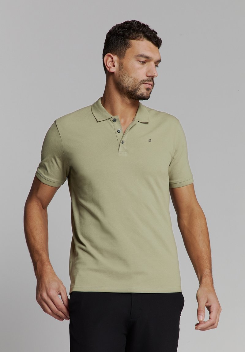 Olijfgroene poloshirt van gestructureerde katoen met een klassieke kraag, twee knopen en een klein logo accent op de borst.