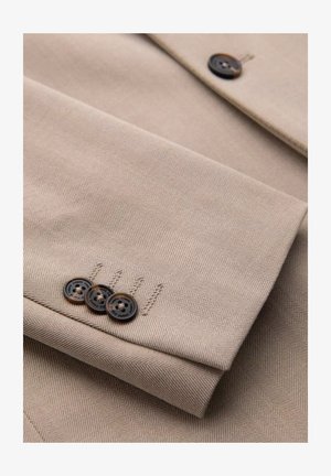 Béžová tkanina s rybí kostí se třemi hnědými knoflíky na manžetě, s hladkou texturou a čistým, skládacím designem.