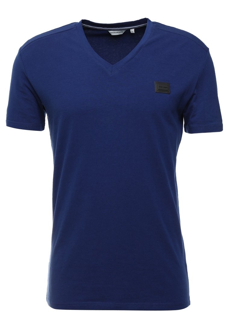 Mörkblå bomulls T-shirt med V-urringning, korta ärmar och en svart rektangulär lapp på bröstet. Slät textur, avslappnad design.