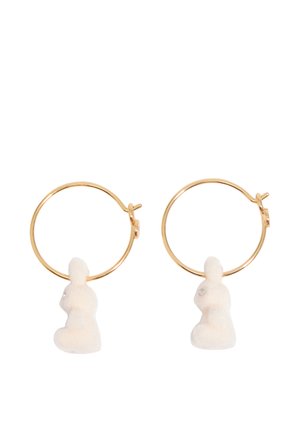 Złote kolczyki koła z małymi białymi zawieszkami w kształcie króliczków wiszącymi wewnątrz każdego koła.