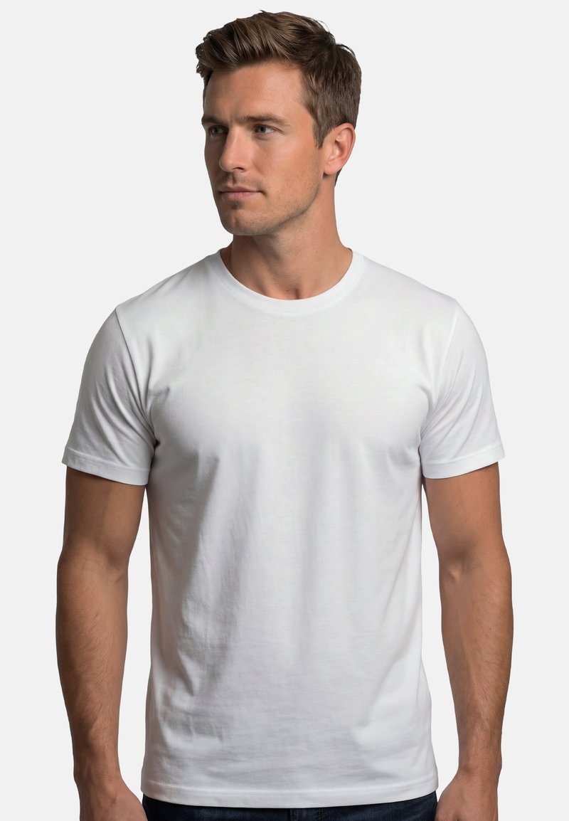 Homme aux cheveux bruns courts portant un t-shirt blanc uni à manches courtes, regardant vers sa gauche sur fond blanc.