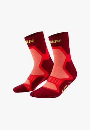 Ein Paar sportlicher Socken bis zur Mitte der Waden in Rot und Pink mit gelber Schrift und geometrischen Mustern, nebeneinander auf weißem Hintergrund gezeigt.