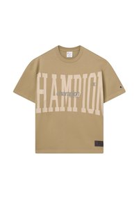 Camiseta de gran tamaño de Champion en color beige, con un gran texto en tono pálido que dice "CHAMPION" en la parte frontal y un logo más pequeño en la manga, cuello redondo y mangas cortas.