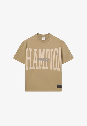 Beige übergroßes Champion-T-Shirt mit großen, hellen "CHAMPION"-Schriftzug auf der Vorderseite und kleinerem Logo auf dem Ärmel, Rundhalsausschnitt und kurzen Ärmeln.
