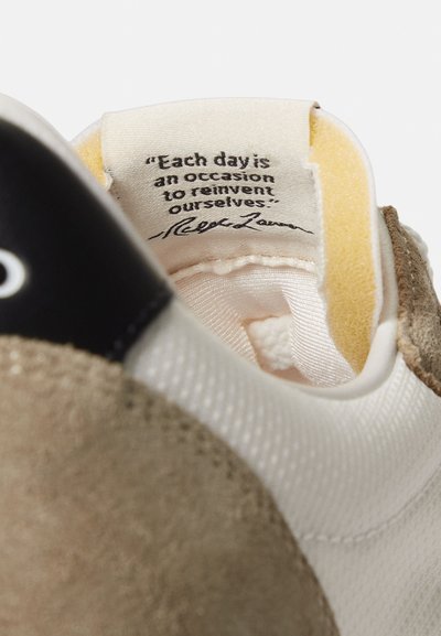 Εσωτερικό παπουτσιού που δείχνει ετικέτα υφάσματος με το απόφθεγμα, «Κάθε μέρα είναι μια ευκαιρία να επανεφεύρουμε τον εαυτό μας.» και την υπογραφή του Ralph Lauren.