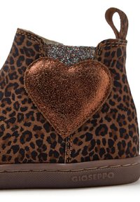 Botki na kostkę w print leopardzi, wykonane z miękkiego materiału, z dużym metalicznym akcentem w kształcie serca w kolorze brązowym oraz teksturowanym, błyszczącym panelem.
