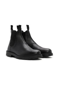 Botas Chelsea de cuero negro con paneles laterales elásticos, tiradores y suelas de goma resistentes. Textura suave con un diseño elegante y minimalista.