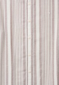 Camisa de algodón a rayas con franjas delgadas alternas en tonos topo y crema, con seis botones y detalles sutiles de costura a lo largo del tapeta.