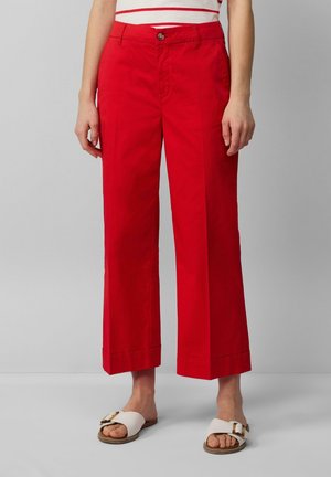 Pantalones anchos de algodón rojo con cintura ajustada y cierre de botón. Largo ligeramente corto, con dobladillo limpio y bolsillos laterales.