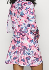 Färgglad klänning med en figurnära långärmad topp i rosa och blå blommönster, utsvängd kjol och en mjuk tygtextur.