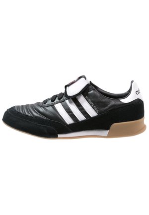 Baskets Adidas noires et blanches avec trois bandes blanches, laçage à l'avant, languette rembourrée et semelle en gomme.