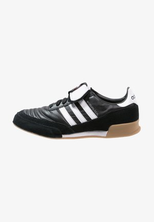 Baskets Adidas noires et blanches avec trois bandes blanches, laçage à l'avant, languette rembourrée et semelle en gomme.