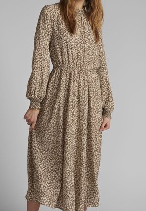 Brązowa, kwiatowa sukienka z długim rękawem, z marszczoną talią, zwiewną spódnicą i elastycznymi mankietami. Lekka tkanina z delikatnymi plisami i nadrukiem.