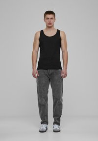 Un top de bumbac negru, asortat cu blugi gri din denim. Blugii au o textură decolorată, cu buzunare standard și o croială lejeră. Adidașii albi completează ținuta.