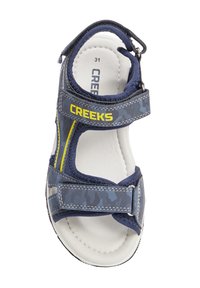 Sandal blu navy con tomaia a fantasia, cinturini regolabili alla caviglia e sul avampiede, e una soletta bianca imbottita. Nome del marchio "CREEKS" visibile.