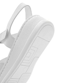 Witte sandaal met een gestructureerde zool, gladde leren banden, een vlak ontwerp en een minimalistische esthetiek. Puntspecificaties zichtbaar op de zool.