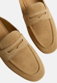 Mocassini in suede color sabbia con un design cucito, stile slip-on e un sottile dettaglio a intaglio nella parte anteriore. Fodera interna liscia.