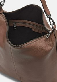 Bolso de mano de cuero marrón con un acabado texturizado, que cuenta con un bolsillo con cremallera en el interior y un forro de tejido suave.