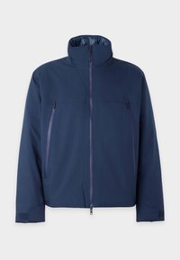 Veste zippée bleu marine avec col montant, deux poches verticales zippées sur la poitrine et poignets réglables à velcro sur les manches.