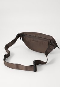 Brown nylon waist bag with a rounded shape, zip closure, adjustable strap, and logo detailing on the side. Smooth texture.