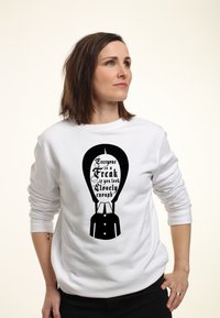 Felpa bianca con un design grafico nero e il testo "Ognuno è uno strano se guardi abbastanza da vicino", stilizzata come un tuxedo.