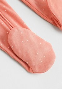 Coral pink cotton leggings with white polka dots, featuring an extended foot section for warmth and comfort. Soft, smooth texture.