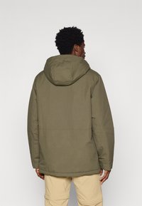 Olivengrøn parka-jakke med stor h�ætte, lavet af blødt stof, med en lige pasform og enkle syninger.