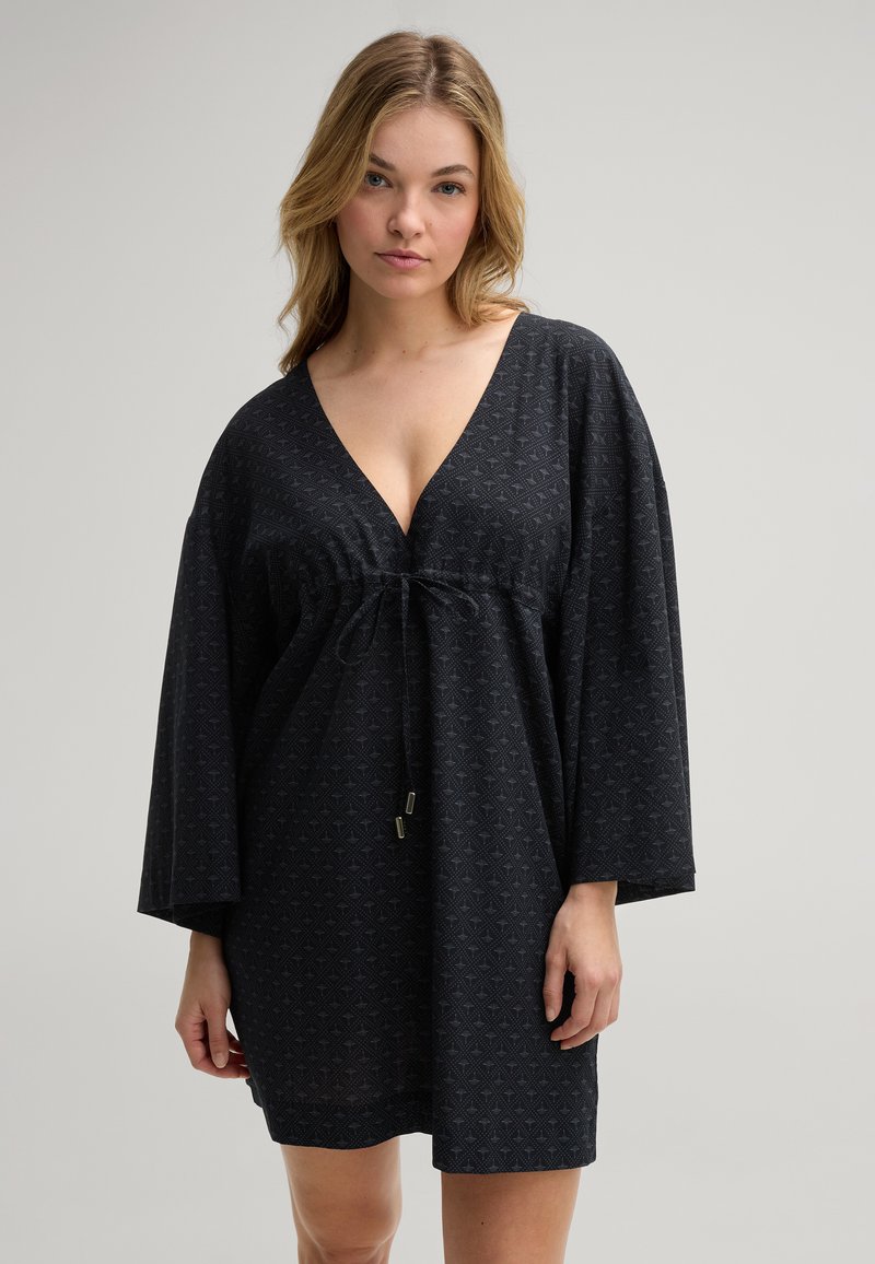 Zwarte jurk met een V-hals en lange mouwen, voorzien van een textuur met geometrisch patroon en een trekkoord taille met metalen accenten.