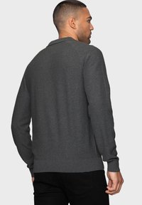 Grauer gestrickter Pullover mit Kragen, langen Ärmeln und gerippten Bündchen und Saum. Glatte Textur, minimalistisches Design und leicht taillierter Schnitt.