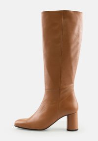 Cizme lungi din piele maro, cu vârf rotund și toc bloc, pe fundal alb.