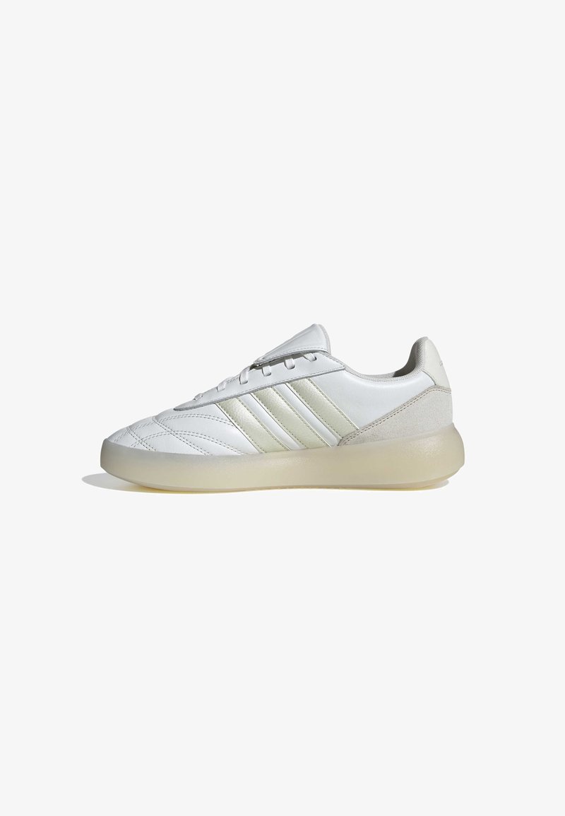 Baskets blanches Adidas avec trois bandes beige clair, fermeture à lacets, détails cousus et semelle beige translucide, vues de profil.